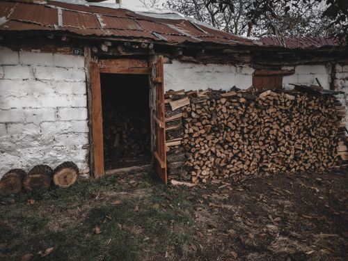 Free A rustic scene with stacked firewood next to an open shed door in an outdoor setting. Stock Photo