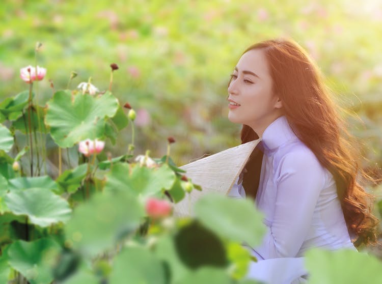 A Woman Wearing A White Ao Dai Near The Plants