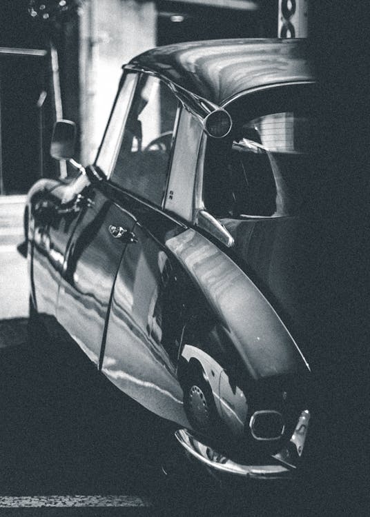Grayscale Photo of Car Parked Beside Building