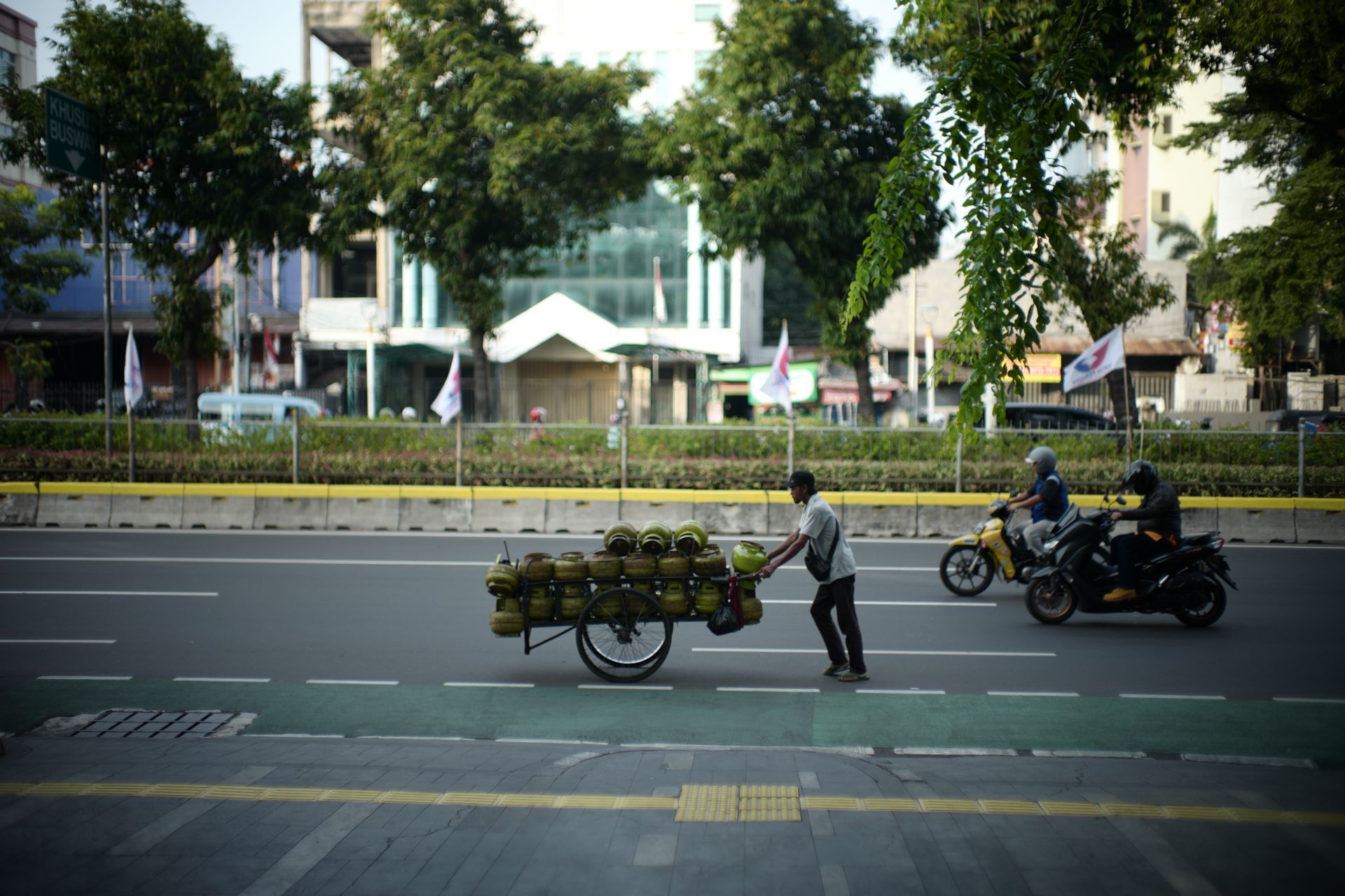 Man pushing cargo cart with gas cylinders on a busy Jakarta street