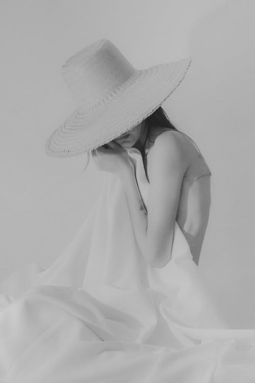 Grayscale Photo of a Woman Covering Her Body with a White Fabric 