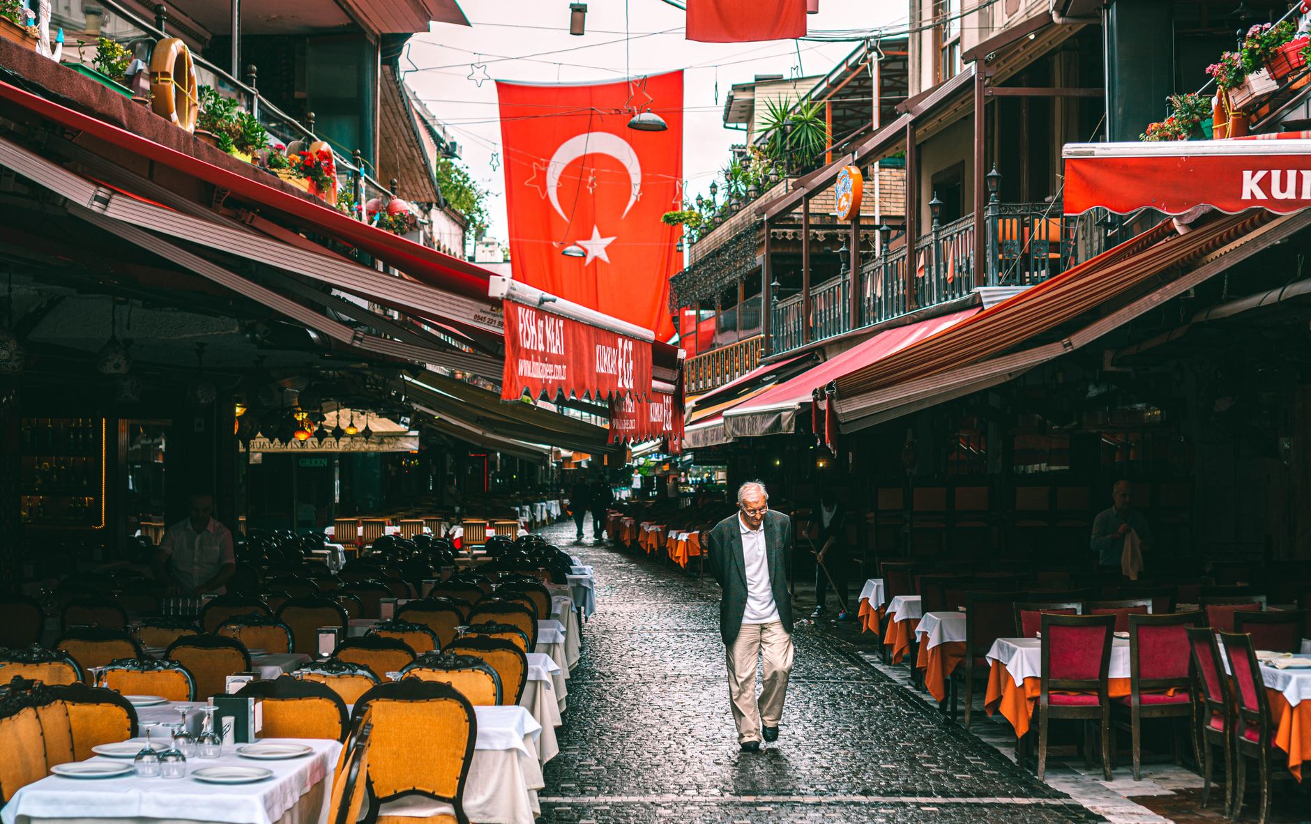 A vibrant street in Istanbul's Kumkapi district with Turkish flags and outdoor cafes.