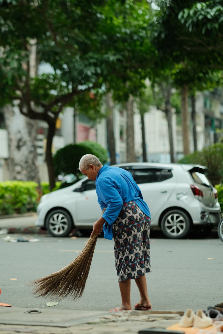 A Woman Sweeping The Road Side