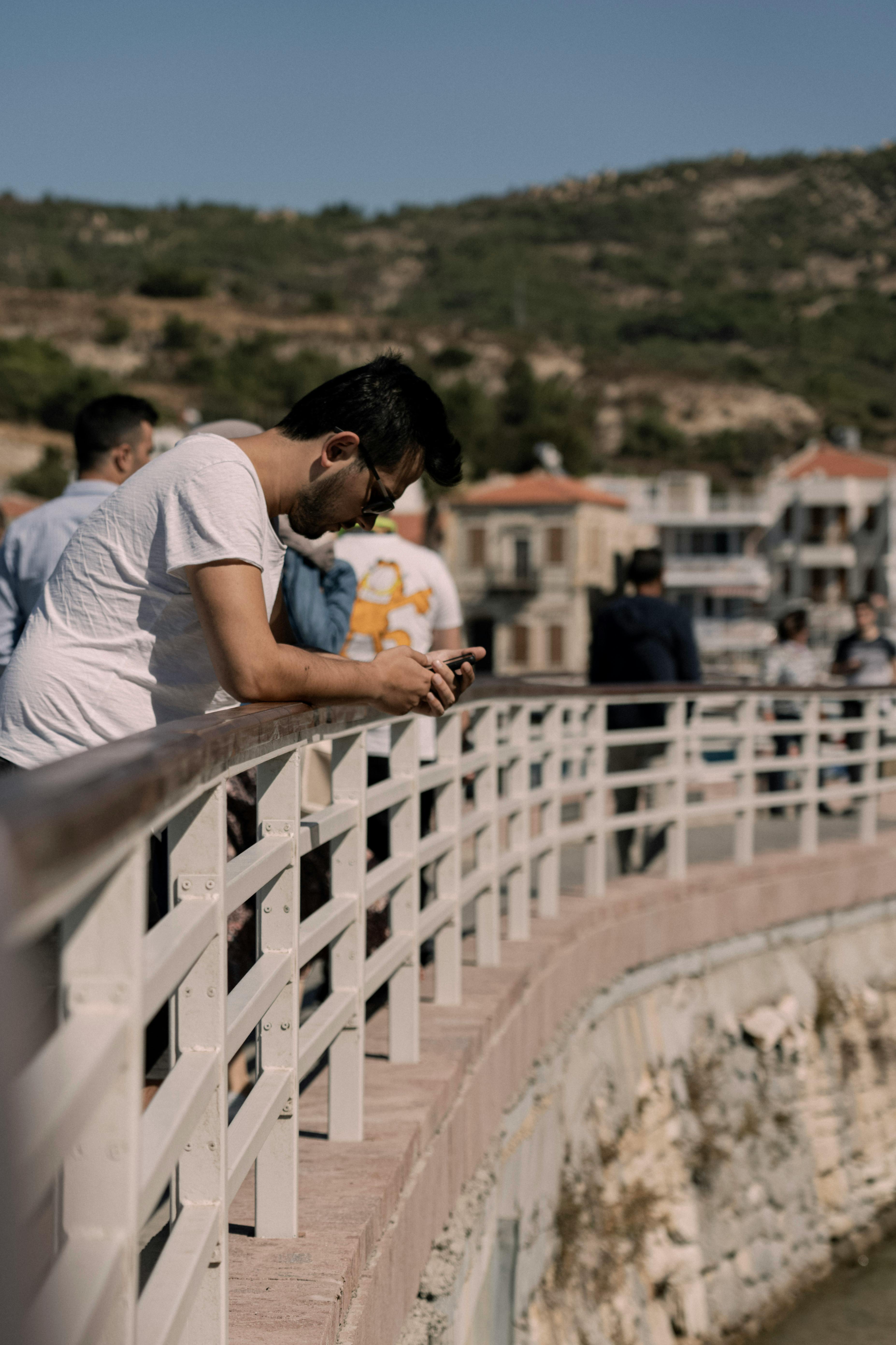 man in white t shirt and woman in white t shirt sitting on white concrete fence