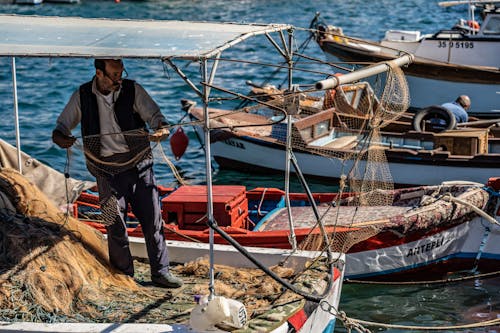 A Fisherman Standing on Boat Docked on Water