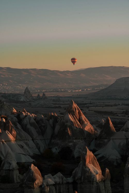 Free A stunning hot air balloon floats above Cappadocia's unique rock formations at sunset. Stock Photo