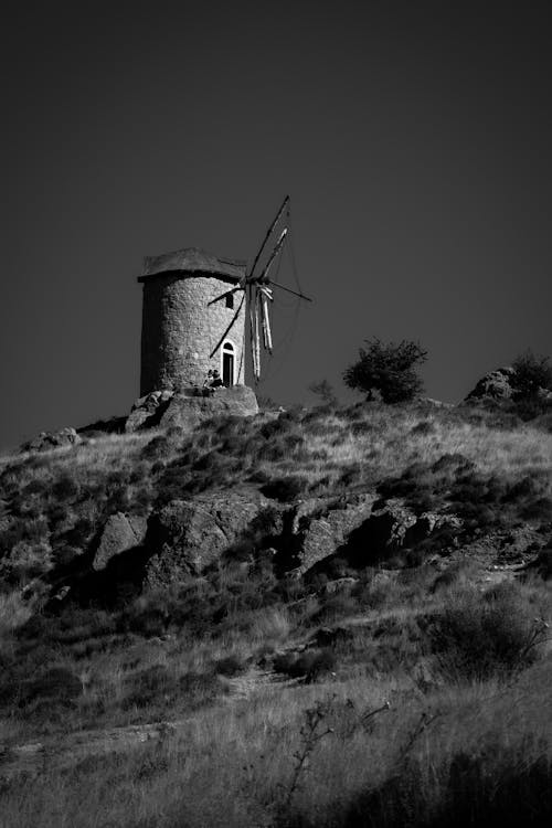 Grayscale Photography of Windmill on Top of a Mountain