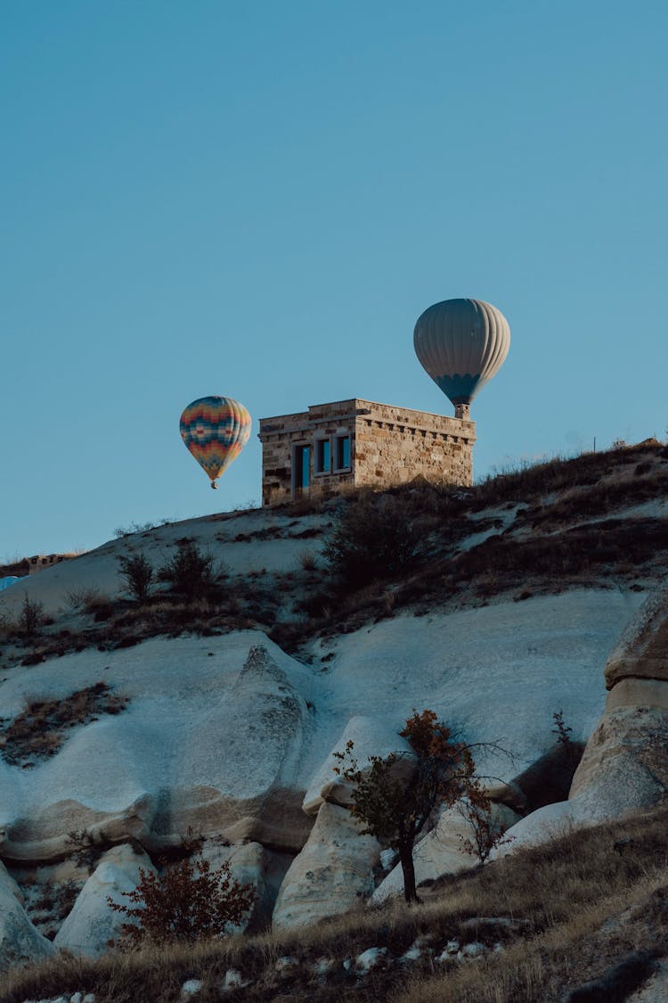 Two Hot Air Balloons Flying Over The Hill 