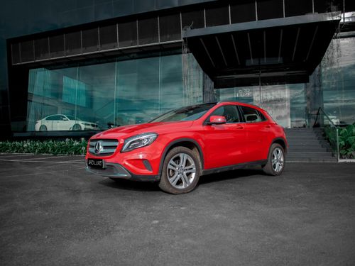 Free Vibrant red SUV, likely a Mercedes, parked in front of a modern glass building in an urban environment. Stock Photo