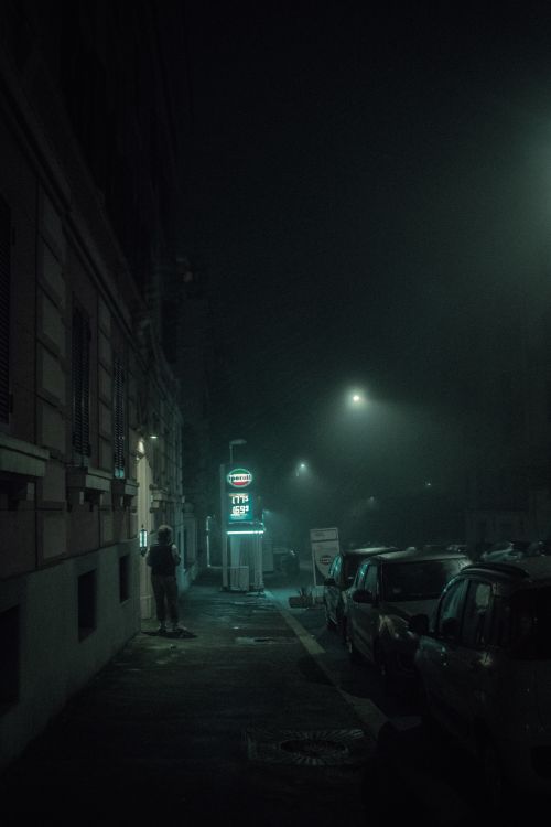 Free Foggy street at night with dim street lights and parked cars, creating an eerie urban atmosphere. Stock Photo