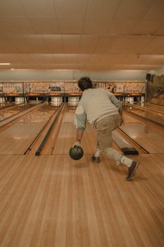 Man releases bowling ball in a vintage styled alley, showcasing leisure and sport.