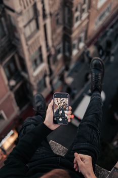 A person captures a cityscape from above with a smartphone, showcasing urban exploration.