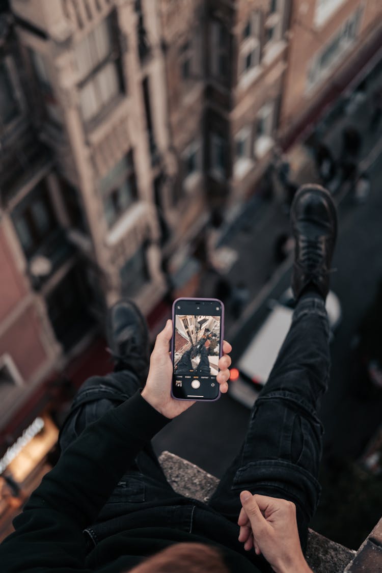 Person Sitting On Roof And Taking Picture