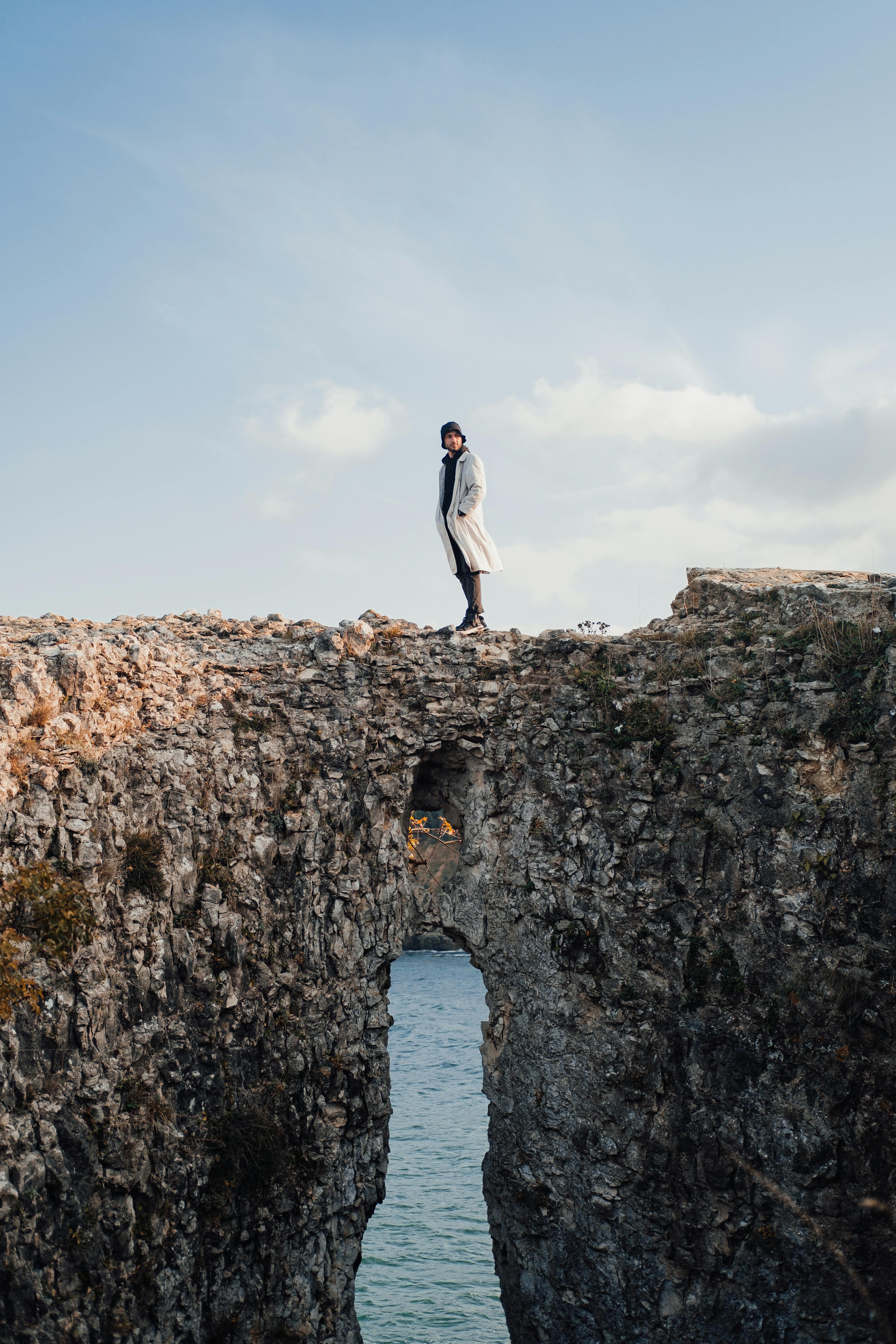 A solitary figure stands on a rocky arch over water in Ağva Merkez, İstanbul, Türkiye.