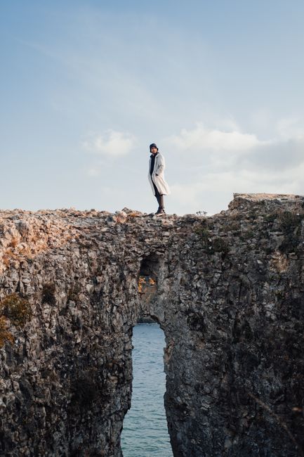 A solitary figure stands on a rocky arch over water in A臒va Merkez, 陌stanbul, T眉rkiye.
