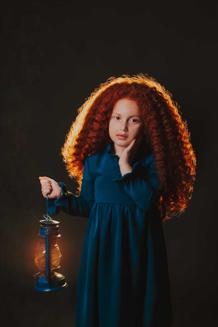 A Young Girl In Blue Dress Holding A Gas Lamp