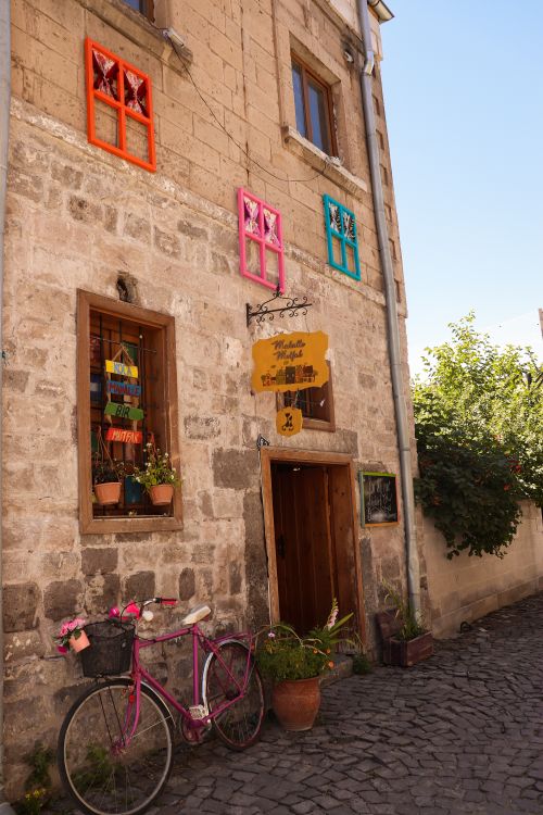 Free A quaint street scene featuring a stone building with colorful windows and a vintage bicycle. Stock Photo
