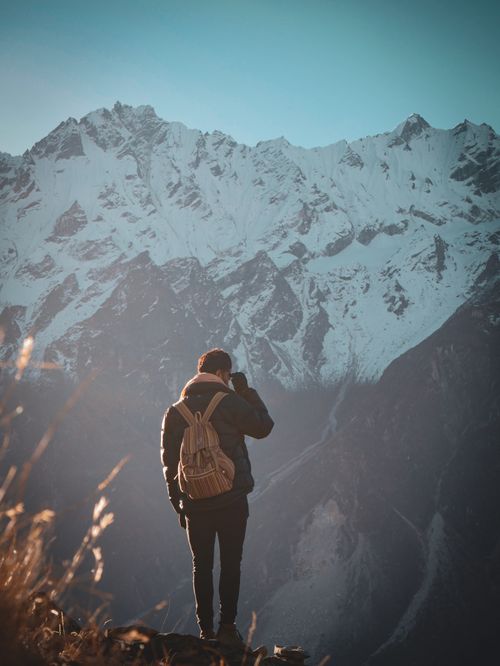 Free A solitary traveler in a puffer jacket admires a breathtaking snow-capped mountain. Stock Photo