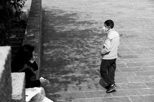 Free Black and white photo of two masked individuals maintaining social distance on a city street. Stock Photo