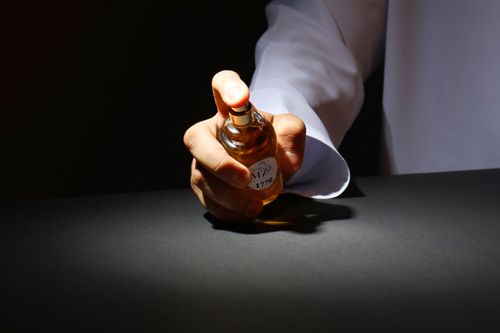 Free A hand elegantly holding a perfume bottle against a dark backdrop, highlighting luxury fragrance. Stock Photo