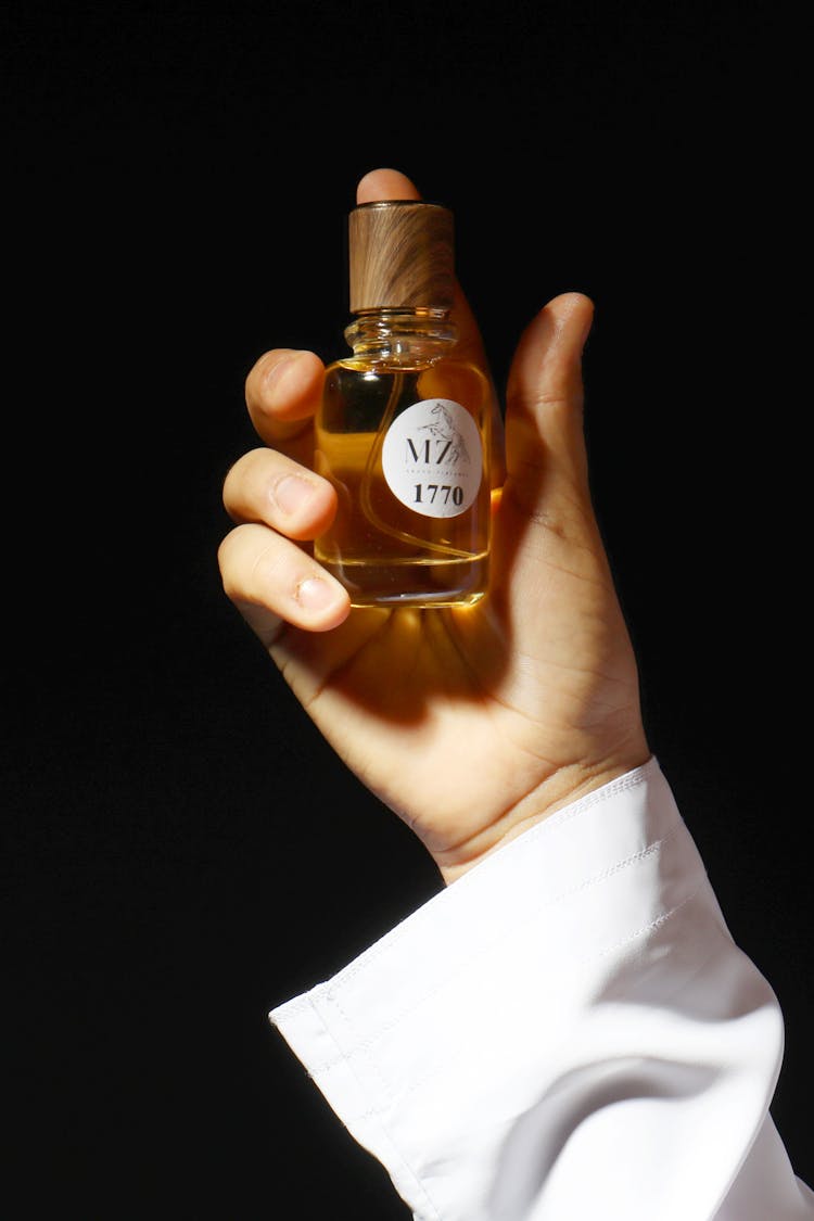 A Person Holding A Bottle Of Perfume 