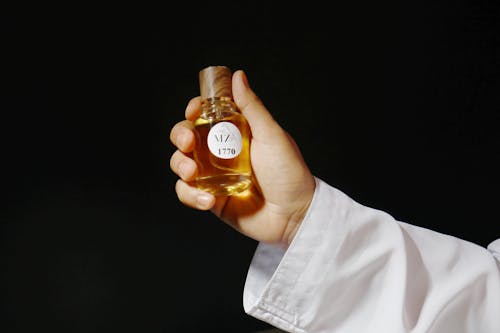 Person Holding Perfume in Glass Bottle