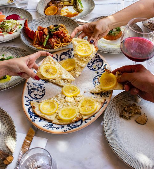 Free A colorful dining scene featuring lemon pizza and wine, perfect for a gourmet dinner setting. Stock Photo