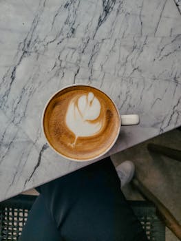 A cup of perfectly crafted latte with artistic foam served on a stylish marble table.