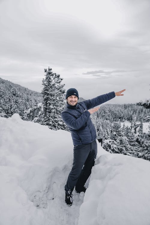 Man in Black Jacket and Black Pants Standing on Snow Covered Ground