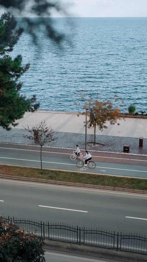 Free Aerial view of cyclists riding along a coastal road in Ordu, Türkiye, with a scenic seaside backdrop. Stock Photo