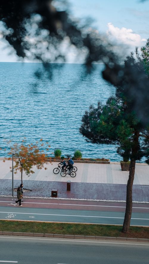Free Cyclists ride along the picturesque Ordu promenade with a stunning sea view, under a clear blue sky. Stock Photo
