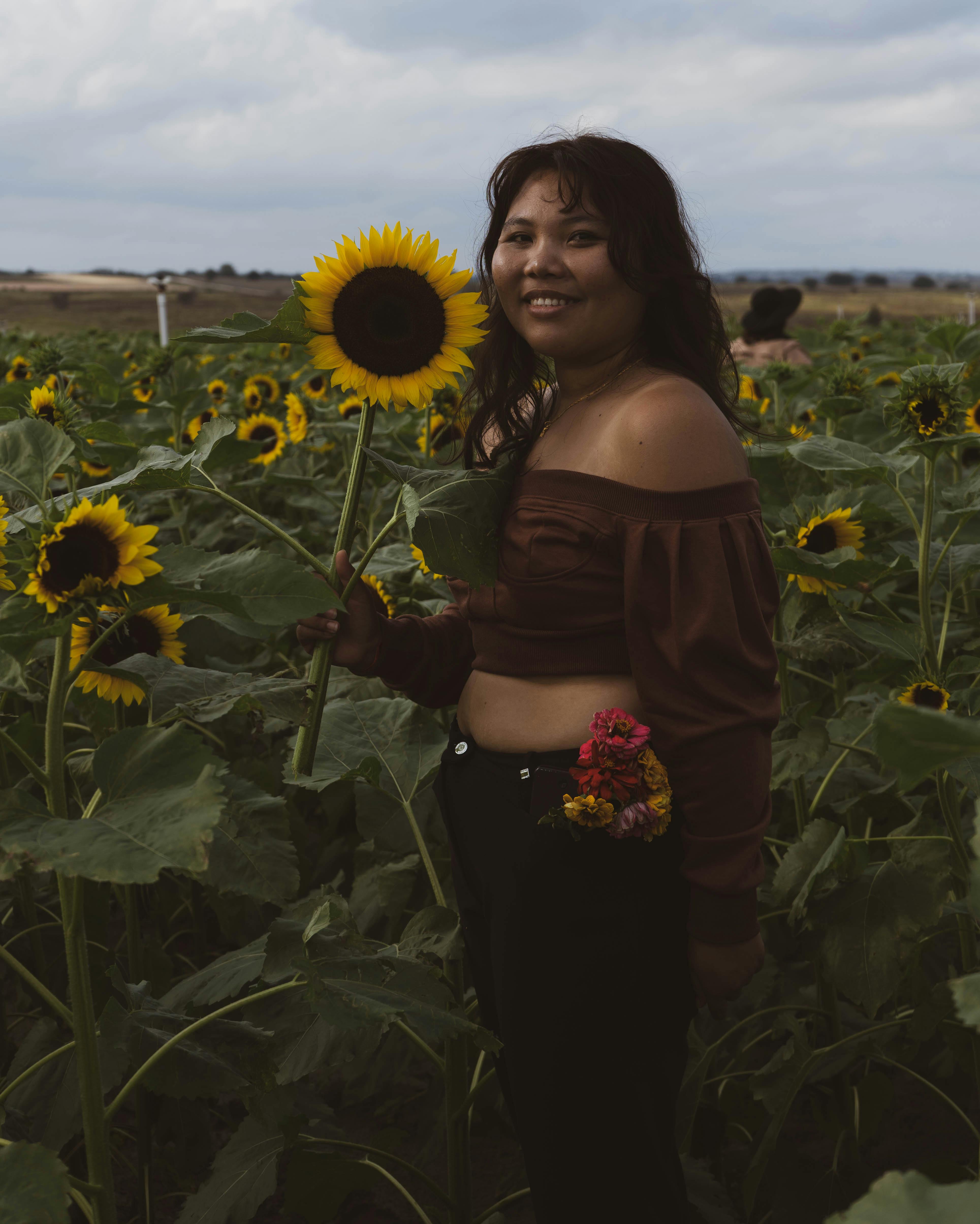 woman in black spaghetti strap dress standing on sunflower field