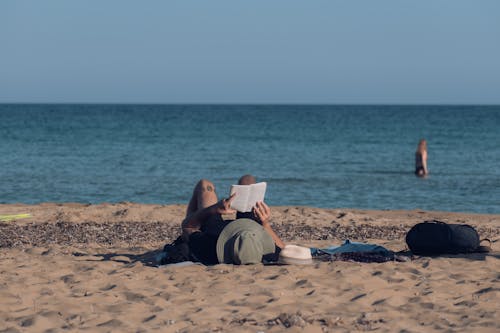 Lying Person Reading Book on Beach