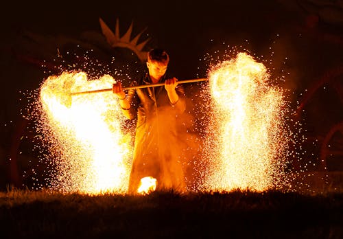 Man in White Robe Holding Stick With Fire