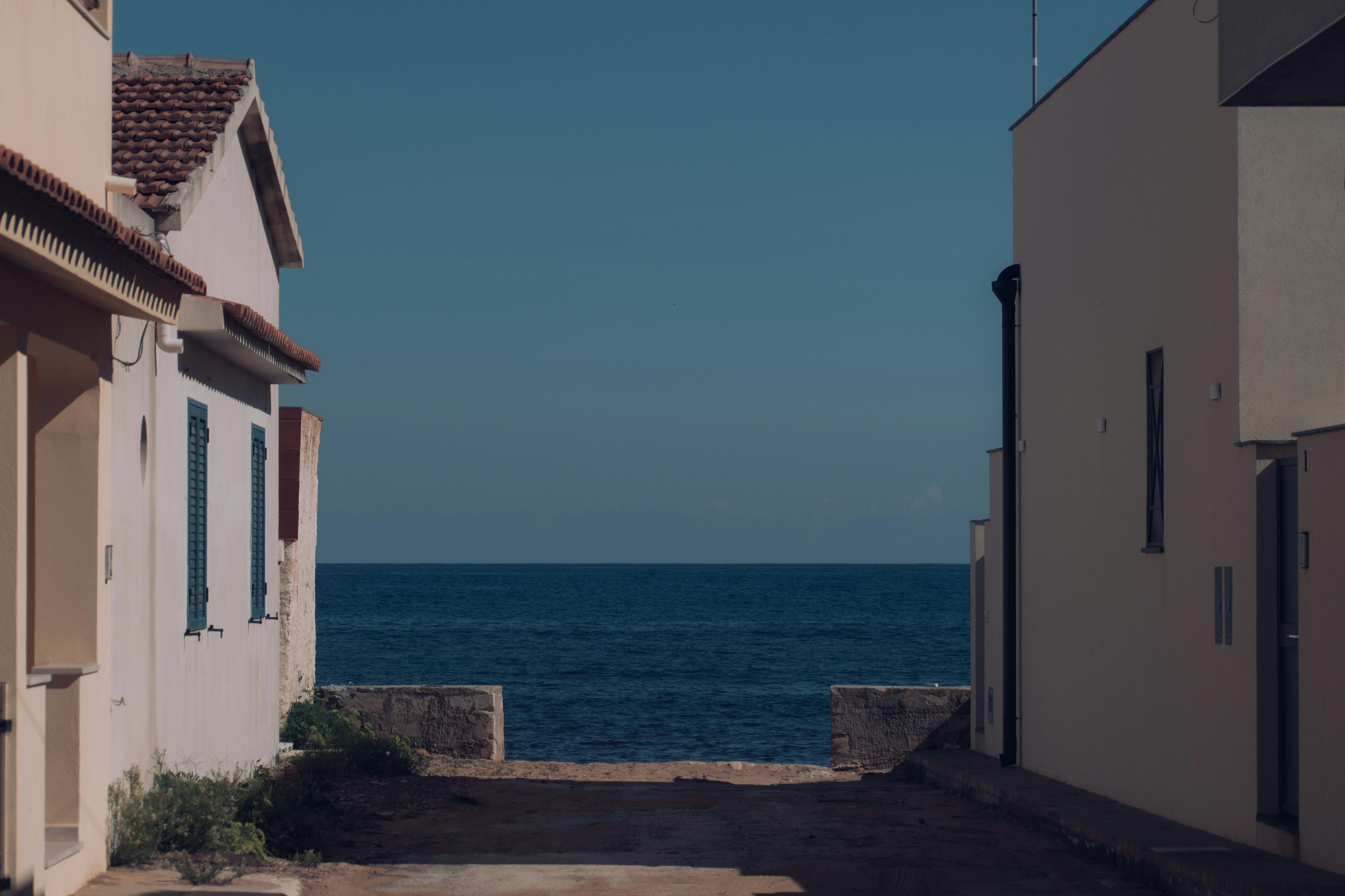 Explore a serene alley in Calabernardo leading to the open sea, capturing Sicilian coastal charm.