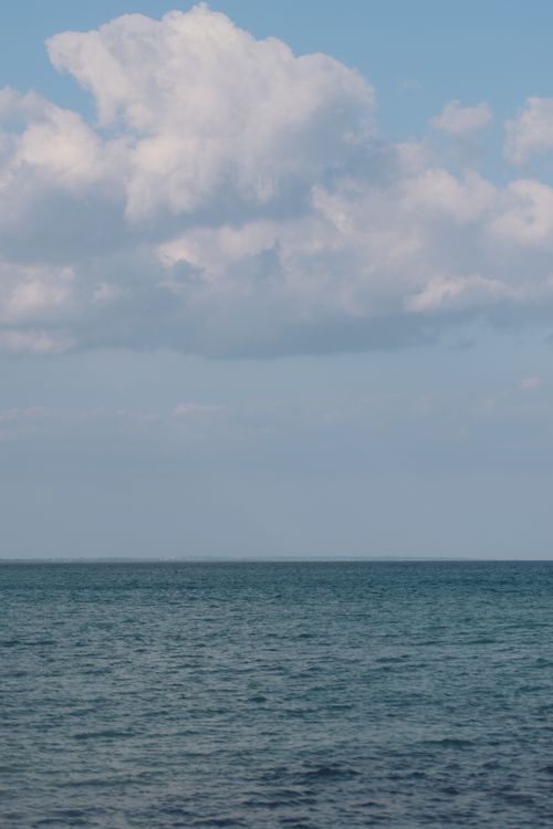 Free Serene view of the blue ocean meeting the sky with white clouds in Sicilia, Italy. Stock Photo