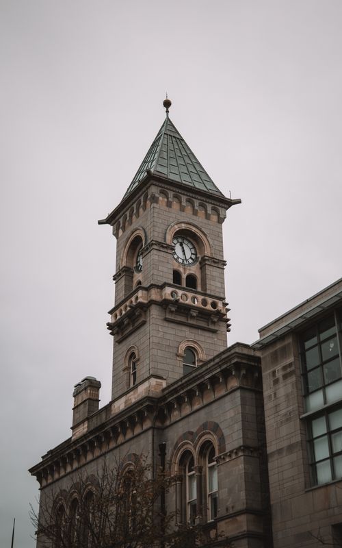 Free Low angle view of a historic clock tower against a cloudy sky in Dún Laoghaire, Ireland. Stock Photo