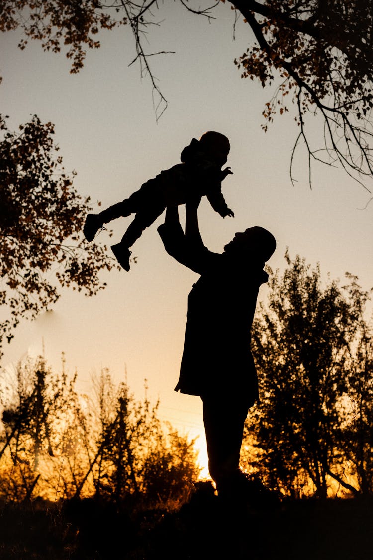 Parent Holding Child In Air For Fun