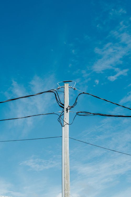 Free A utility pole with electric wires against a clear blue sky, showcasing simplicity and infrastructure. Stock Photo