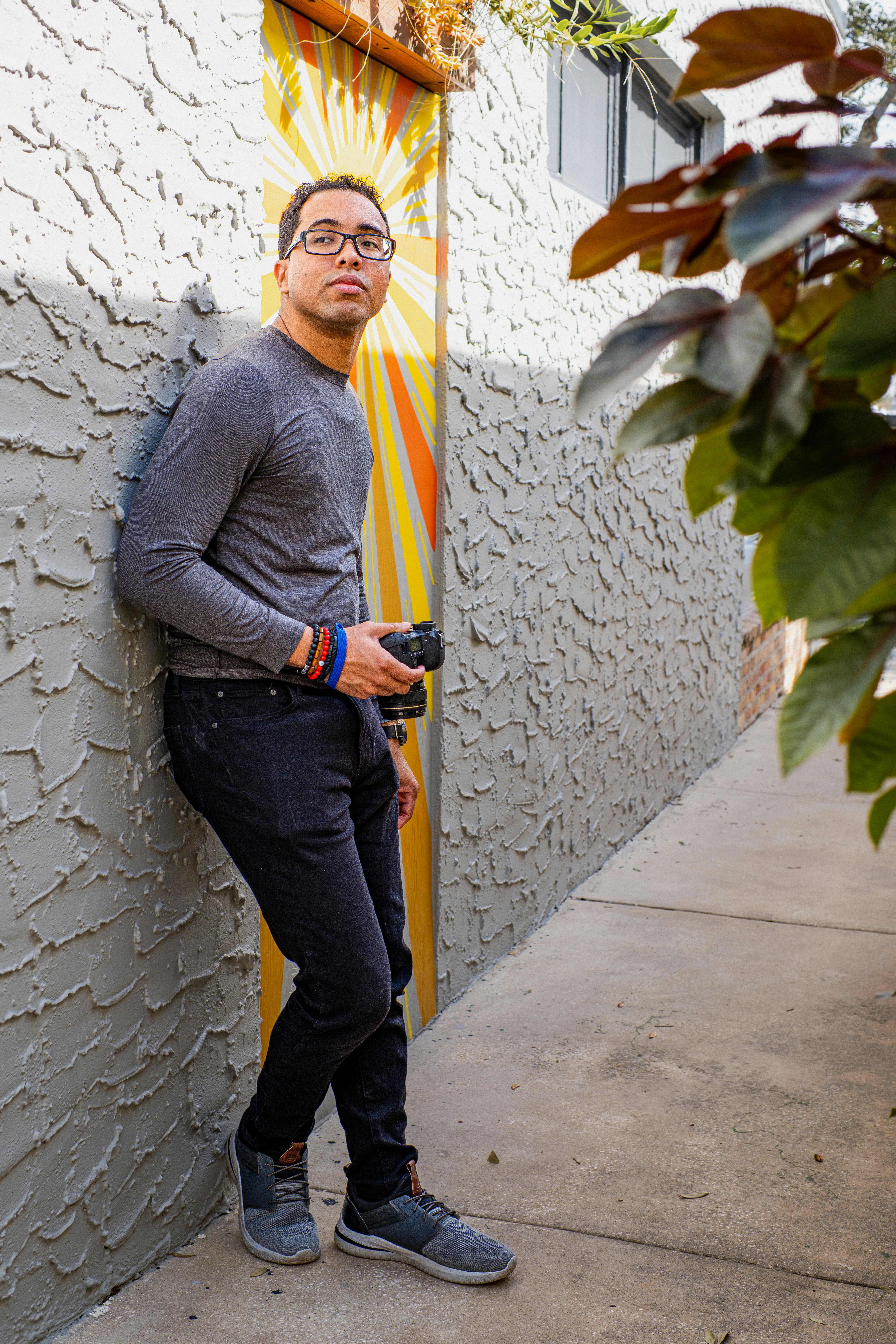 man in gray blazer and black pants standing beside green plant