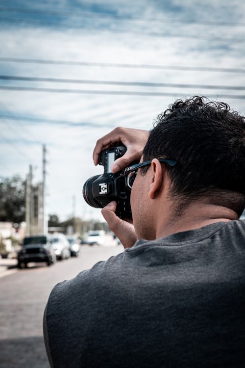 Free A photographer takes pictures in a bustling urban street setting during the daytime. Stock Photo