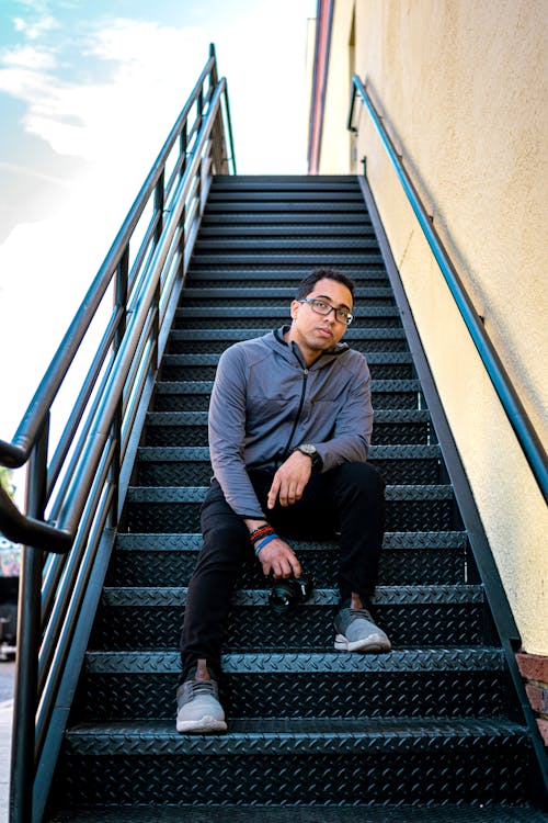 Man Sitting on Metal Stairs