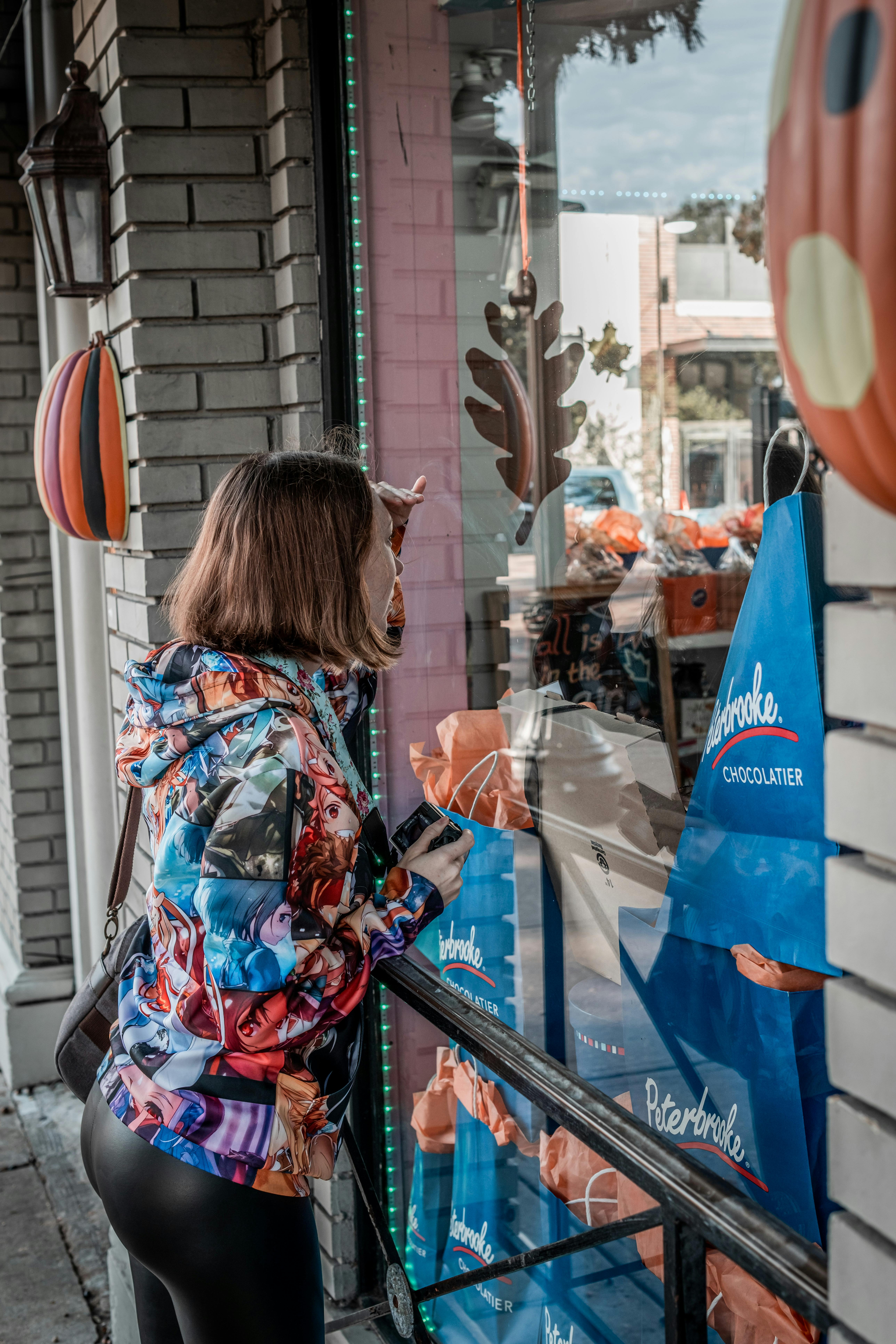 woman in blue and red floral shirt standing in front of store