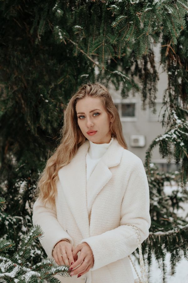 Woman in camel coat over all cream outfit