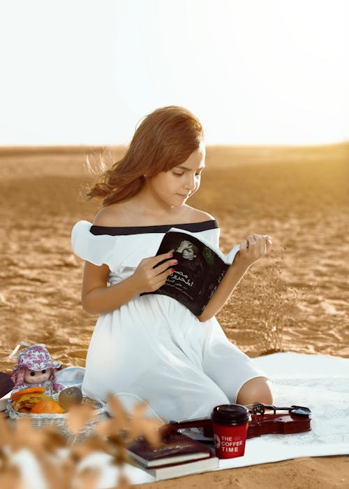 Kneeling Woman on Picnic Blanket Reading Book