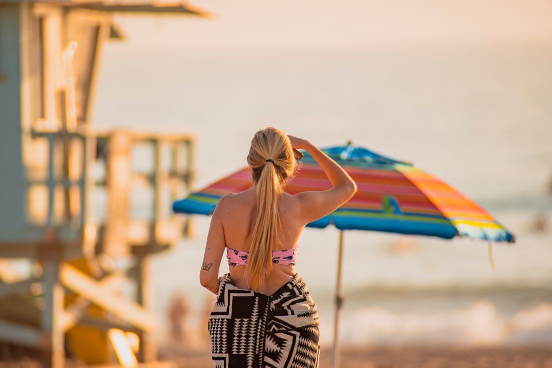 Frau mit farbigem Sonnenschirm am Strand, Ganzkörperaufnahme