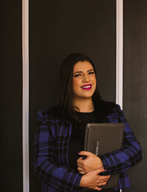 Free Smiling woman in a plaid blazer holding a tablet against a dark background. Stock Photo