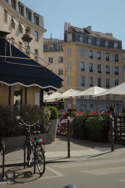 Sunny day in Paris with quaint cafes and classic architecture in view.