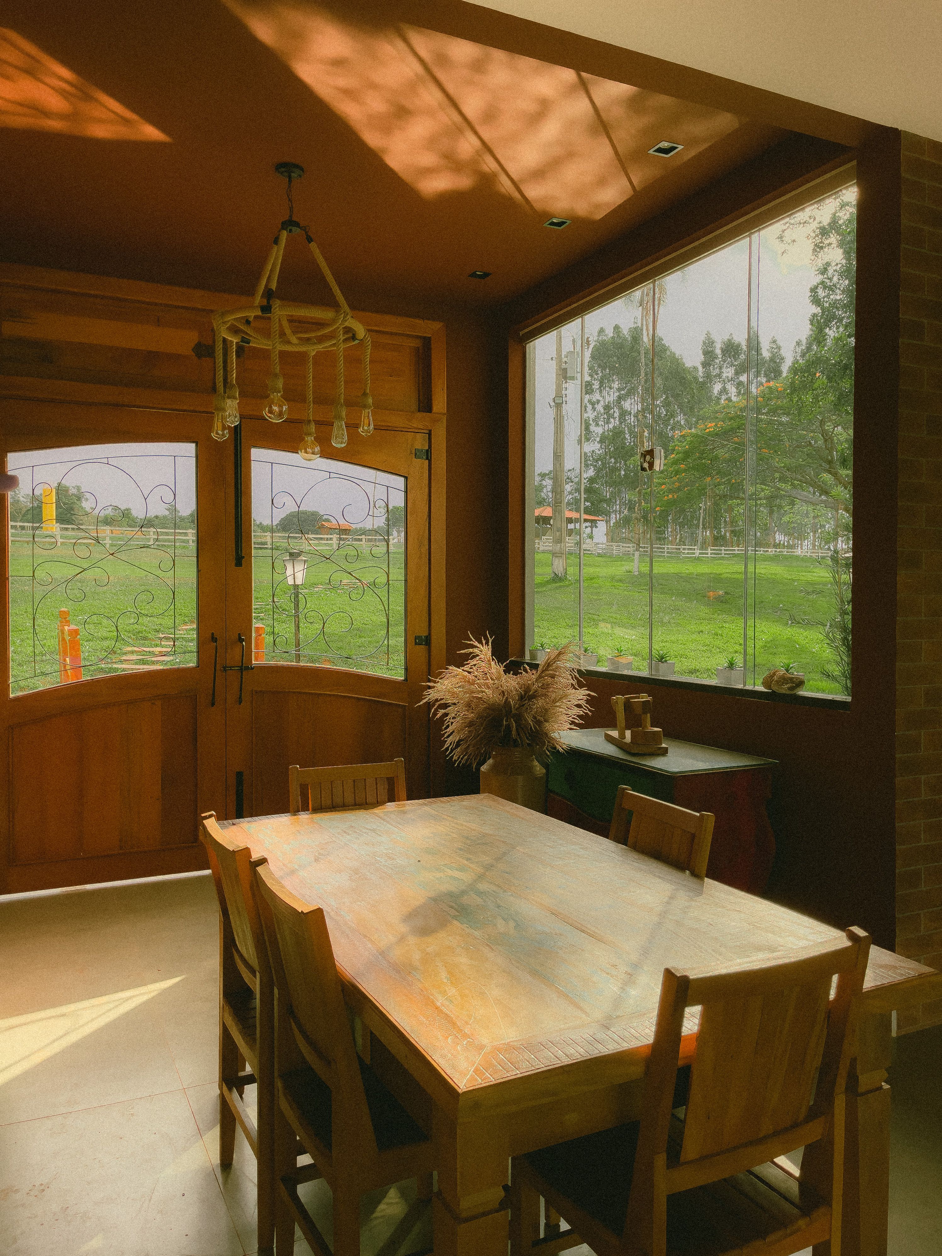Dining room with a long wooden table and garden views, photo by Caio Mantovani on Pexels