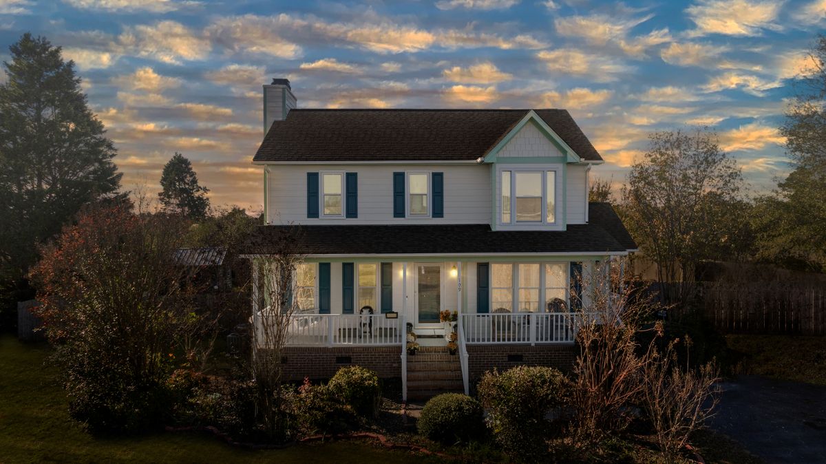 Two-story suburban house with a front porch in warm evening light